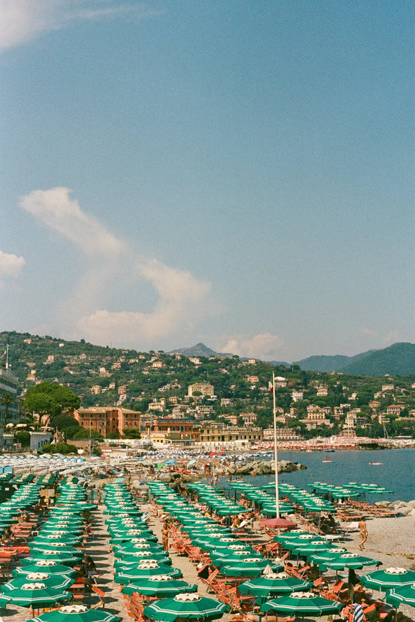 Sunlit Italian Riviera Beach Scene with Green Umbrellas